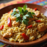 Arroz con Pollo Colombiano servido en plato rústico con cilantro y pimiento rojo sobre mantel colorido.