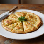 Tortilla de patatas receta para 2 servida en plato con perejil y cortada en porciones