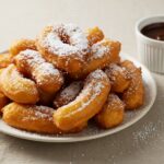 Churros de papa recién fritos y espolvoreados con azúcar, una deliciosa presentación de la receta de churros de papa.