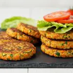 Finished hamburguesas de calabacín served with fresh vegetables, perfect for a healthy meal.