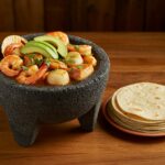 Molcajete de mariscos fácil terminado, decorado con aguacate y cilantro, ideal para disfrutar en una celebración.