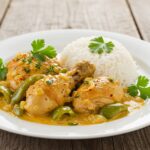 Plato terminado de pollo en pepitoria, con hierbas frescas y arroz, ideal para disfrutar de la receta de pollo pepitoria tradicional.
