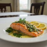 Salmón al horno terminado con mantequilla de ajo y hierbas, ideal para disfrutar en una cena.