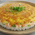 Finished golden-brown sushi bake with garnishes, ready to serve.