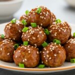Albóndigas de pollo teriyaki dulces y saladas, decoradas con semillas de sésamo y cebollín.