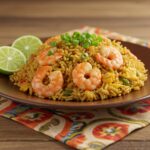 Plato final de arroz frito con camarones, listo para disfrutar, acompañado de gajos de lima.