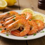 Camarones al horno servidos con rodajas de limón y hierbas frescas, ideales para disfrutar.