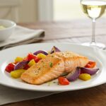 Filetes de salmón en freidora de aire perfectamente cocidos y servidos con verduras asadas.