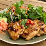 Pollo Estilo Vietnamita a la Parrilla servido con ensalada y hierbas frescas, ideal para una comida aromática.