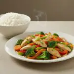 Plated salteado de pollo con verduras with garnishes, perfect for a vibrant meal.