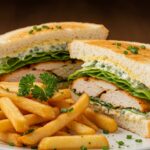 Sándwich césar crujiente de pollo terminado, acompañado de papas fritas, listo para disfrutar.