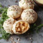 Bolas de relleno de pavo con arándanos doradas y crujientes en una fuente blanca, adornadas con un toque de arándanos frescos y menta, presentadas en un estilo elegante y festivo