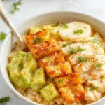A vibrant bowl filled with fluffy white rice, tender chunks of seasoned chicken, bright yellow elote kernels, garnished with fresh cilantro and lime wedges. The bowl is colorful and inviting, showcasing a balanced blend of textures and flavors, with the ingredients arranged appealingly against a rustic wooden background.