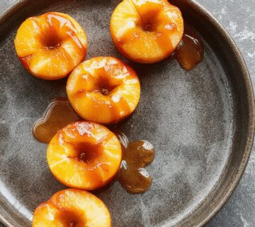 A close-up of shiny white caramel apples coated with a glossy glaze, decorated with elegant drizzles and tiny sparkles, arranged on a sophisticated platter with soft lighting highlighting their smooth texture and shimmering finish.