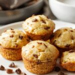 Mini muffins de panqueque dorados y esponjosos en un plato blanco, con una textura ligera y miga visible, decorados con migajas de azúcar y acompañados de sirope