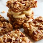 Golden-brown banana oatmeal bars arranged on a rustic wooden platter, showcasing a slightly crumbly texture with visible banana slices and oats, garnished with a sprinkle of chopped nuts and a drizzle of honey for a tempting, wholesome snack.