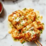 Brochetas de pollo a la parrilla con un glaseado dorado, acompañadas de queso parmesano rallado y ajo finamente picado, presentadas en una bandeja de madera con ramitas de romero y segmentos de limón, mostrando una textura jugosa y crujiente en cada pieza.
