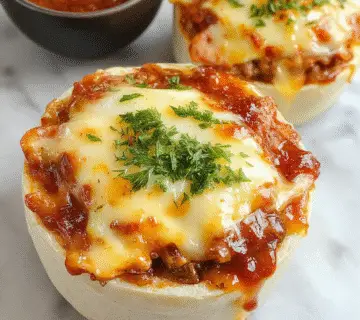 Cazuela de hamburguesa con queso y tocino vista desde arriba, mostrando una bandeja dorada con capas de carne molida, queso fundido y crujiente tocino en la superficie, con queso derretido chisporroteando y trozos de tocino crocante en la parte superior, decorada con perejil fresco en los bordes y servida en una bandeja de horno de cerámica beige.