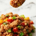 A vibrant stir-fry with ground turkey, red and green bell peppers, and sliced onions in a glossy sauce, served in a white bowl against a rustic wooden backdrop.