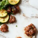 A vibrant plate of zucchini beef stir-fry arranged neatly, featuring julienned zucchini and tender beef strips coated in a glossy sauce, garnished with sesame seeds and chopped green onions on a rustic wooden table.