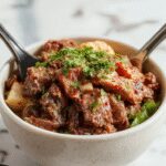 A vibrant Korean ground beef bowl featuring seasoned beef atop fluffy white rice, garnished with sliced green onions, sesame seeds, and a drizzle of sauce, served in a stylish bowl on a wooden table.