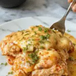 Plato de pollo con mozzarella en salsa cremosa de albahaca, presentado en un plato blanco con mozzarella derretida cubriendo el pollo, rodeado de hojas de albahaca fresca y una salsa verde vibrante, textura cremosa con el queso fundido y pollo dorado en la superficie