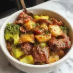 A vibrant dish of Carne de Res y Brócoli Chino served on a white plate. The beef strips are glazed in a glossy dark soy sauce, garnished with fresh green broccoli florets. The presentation highlights the rich, tender meat contrasting with the bright, crisp broccoli, arranged neatly with a sprinkle of sesame seeds and chopped green onions for a colorful touch. In the background, a pair of chopsticks rests beside the plate, evoking an authentic Chinese cuisine vibe.